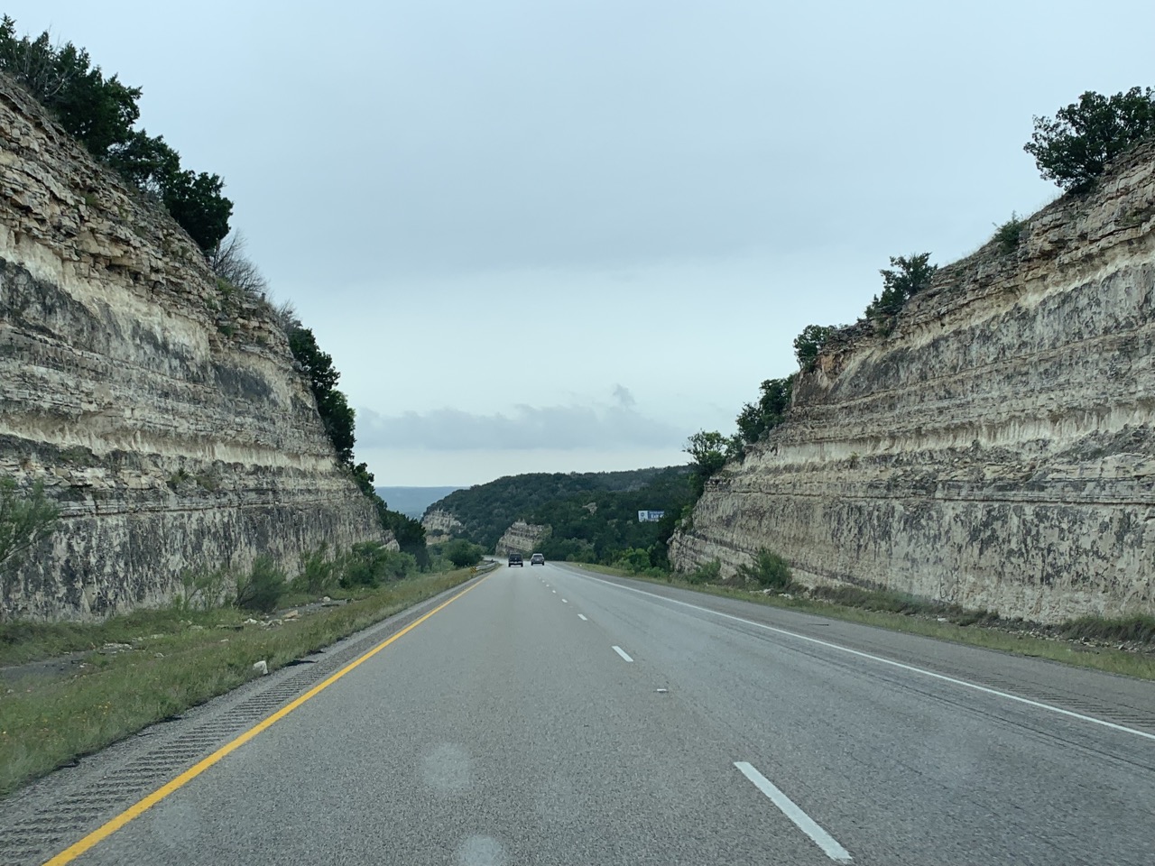 Road cut through a rocky hill.